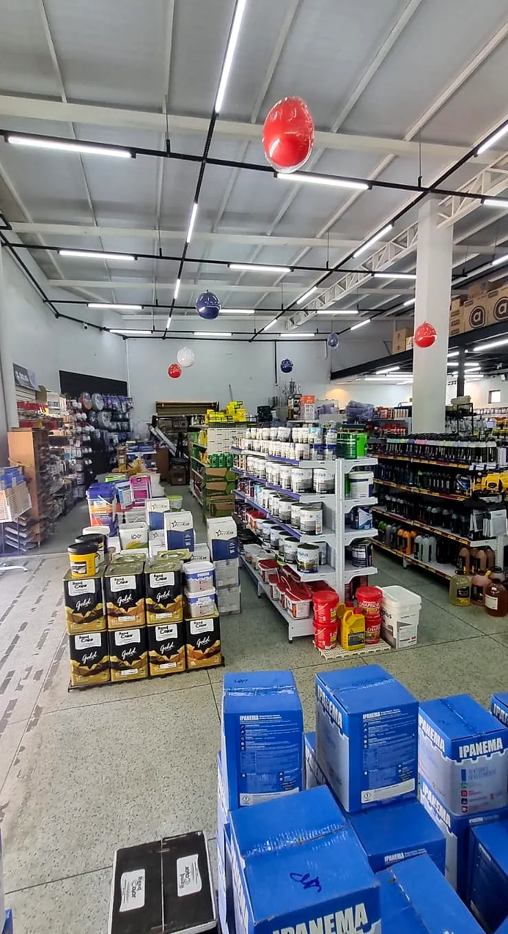 Visão geral do salão da Comercial Central com tintas, linha automotiva e corredores de ferragens
